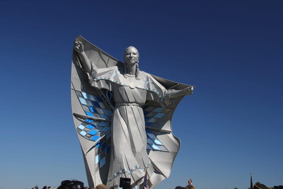 Statue of a native american person holding a diamond quilt over their shoulders