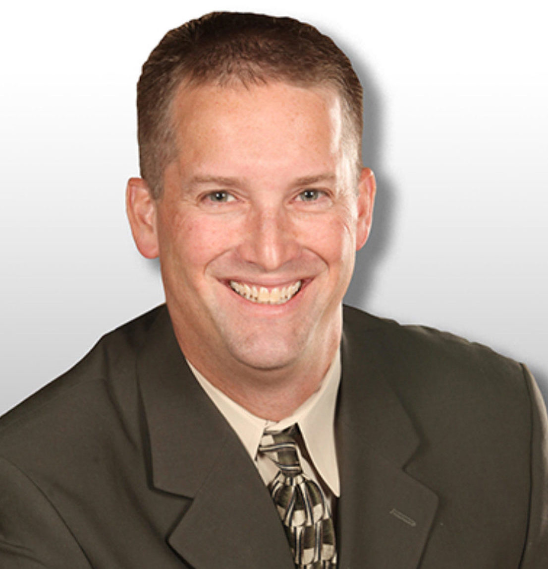 Smiling man with brown hair and a gray suit and tie