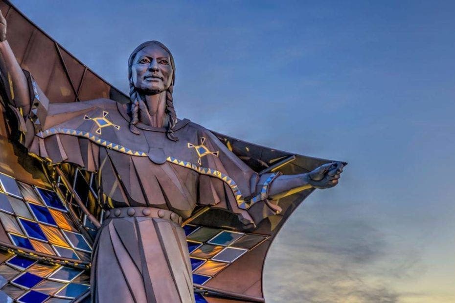 Statue of a native american person holding a diamond quilt over their shoulders