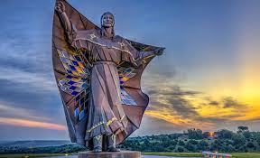 Statue of a native american person holding a diamond quilt over their shoulders