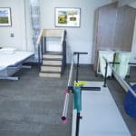 interior of a physical therapy office with medical equipment and photos of sunflowers on the wall.