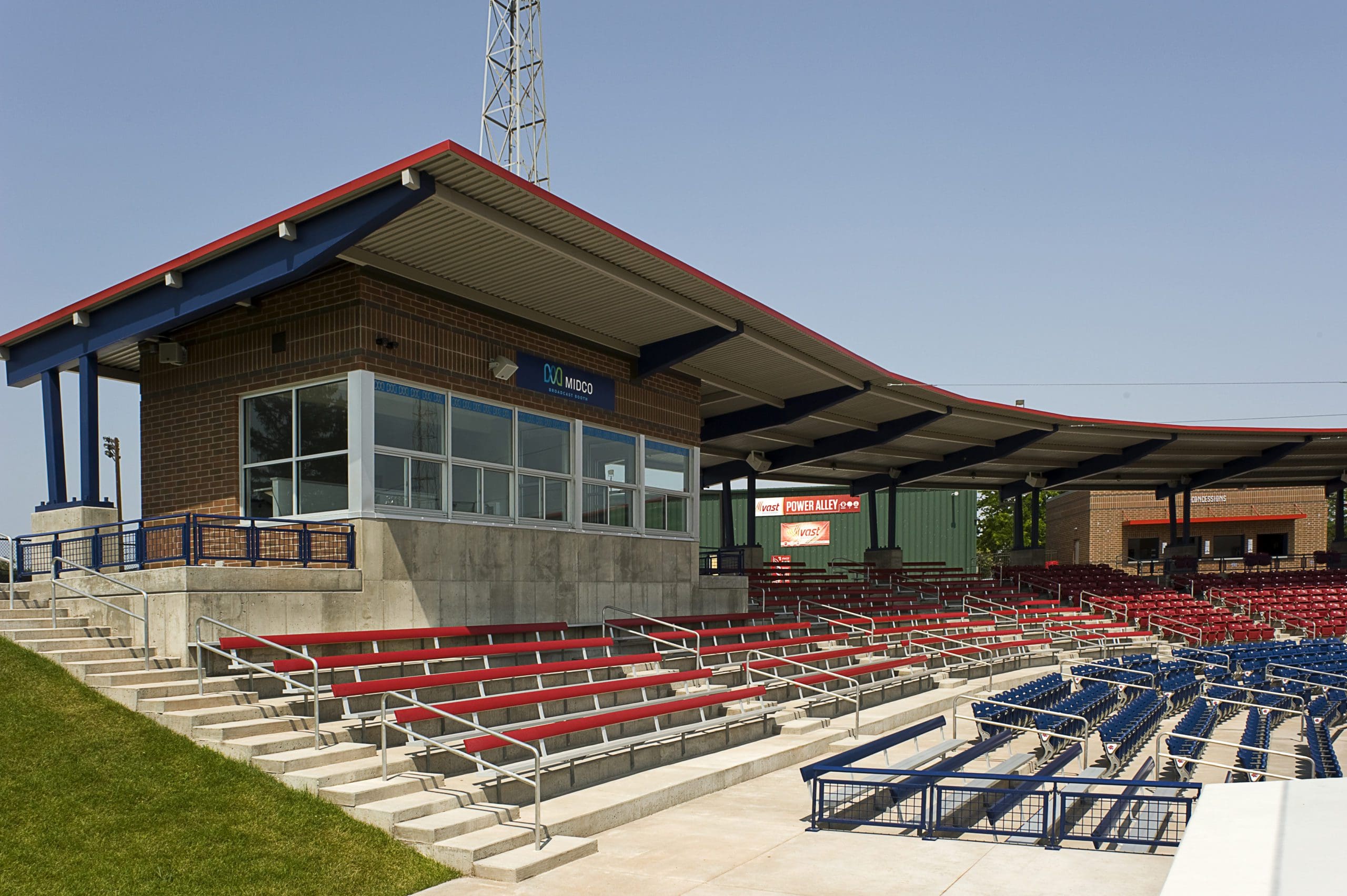 baseball stadium with red and blue seats and a brick announcer lodge